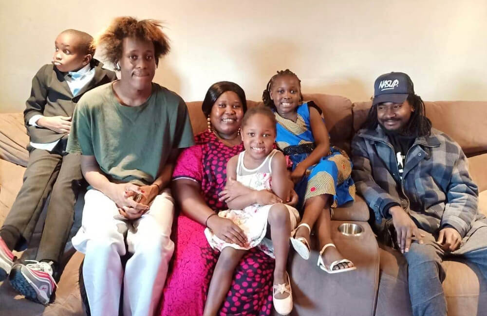 A family sit together on a sofa.